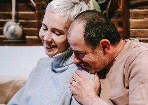 Man with head on shoulder of woman smiling together.
